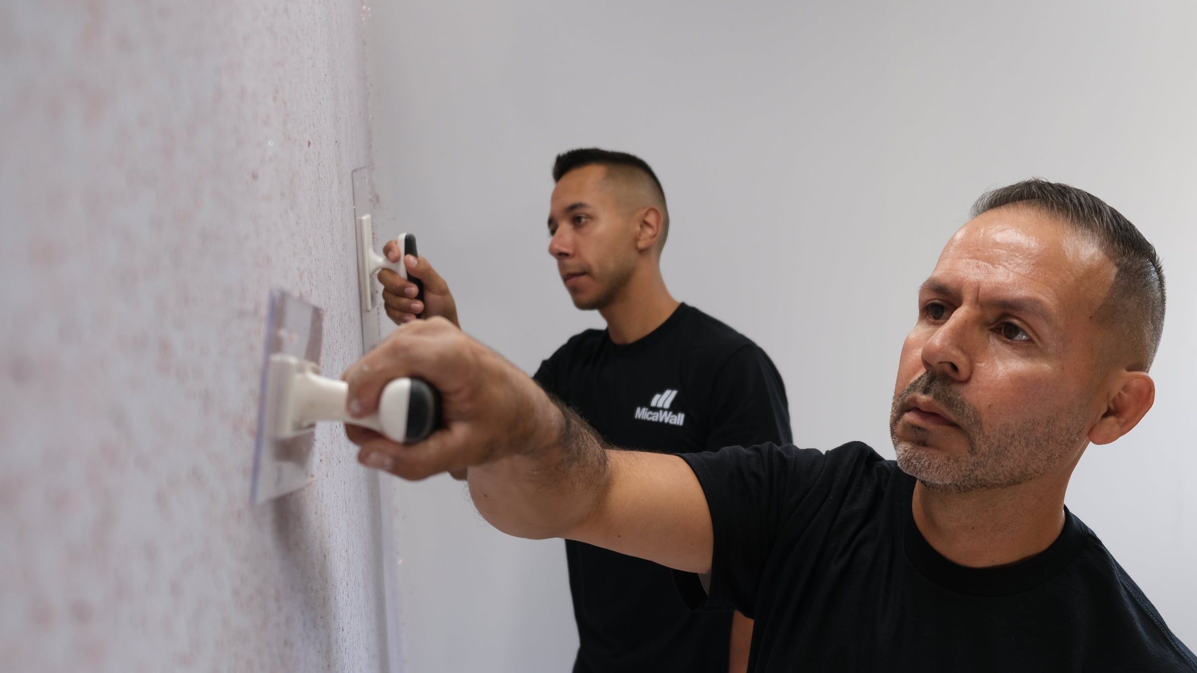Two men installing MicaWall using the Ghost Trowel. Stone FX, MetalFX and GlowFX